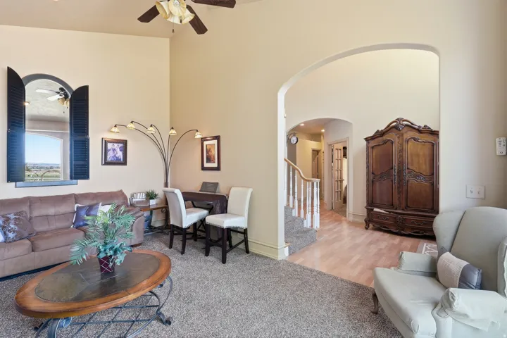 Arched window with exterior shutters, high ceilings, ceiling fan, and staircase with wood banister