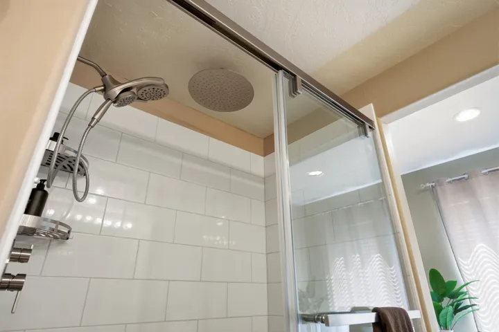 White subway tile shower with a dual shower head system and a rainfall shower head