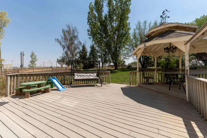 Expansive outdoor decking, built-in wooden gazebo with seating, and a spacious grassy area