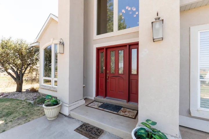 Stucco exterior featuring a prominent red double-door entry with decorative glass inserts, an arched window, and a tall sidelight window