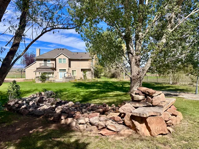 Expansive green lawn, stone-stacked landscaping, mature trees, rear deck, and a gazebo structure