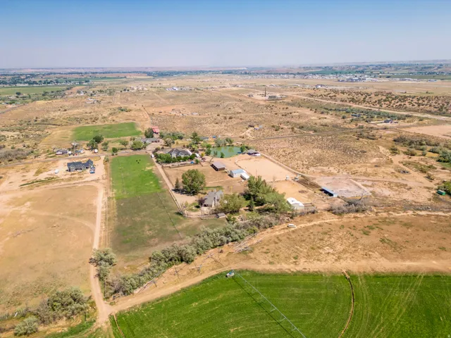 Expansive property featuring multiple structures, a pond, and cultivated green areas