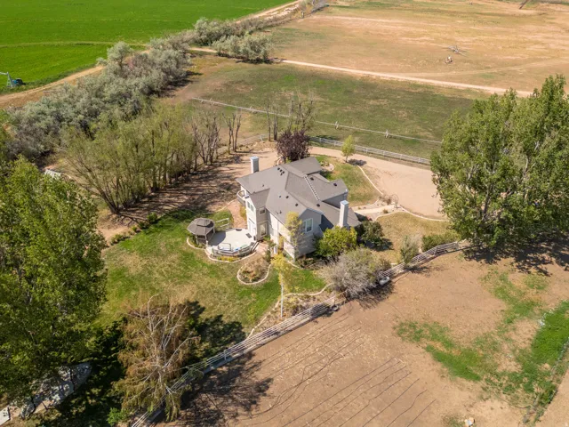 Expansive exterior with a shingled roof, a large back patio, a built-in gazebo, and mature trees surrounding the property