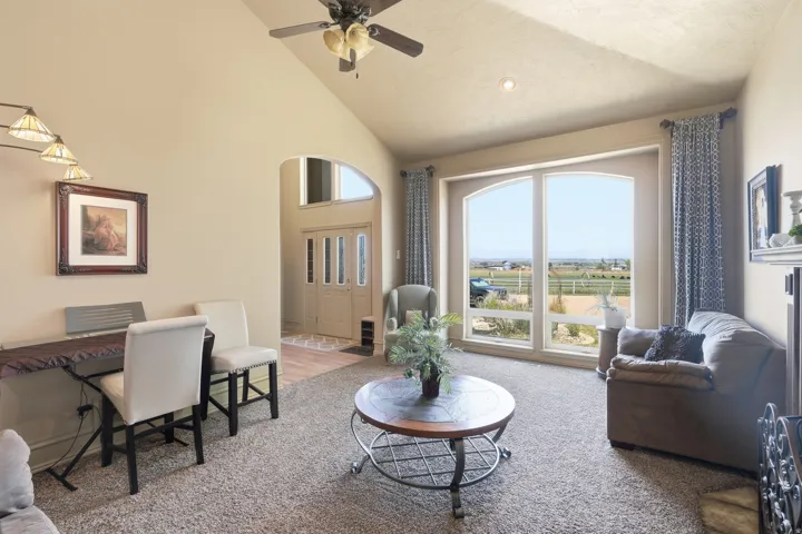 Vaulted ceiling with ceiling fan, arched windows, and a carpeted floor