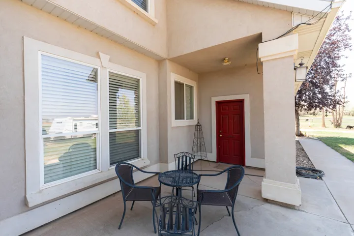 Covered concrete patio with a red entry door, exterior column, and sconce lighting