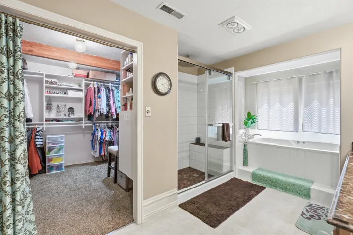 Walk-in closet with built-in shelving, organized hanging storage, and exposed wood beam