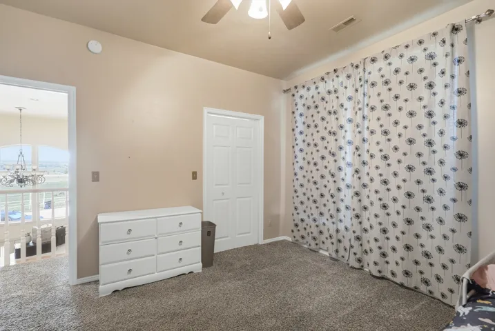 Light-colored walls, carpeted flooring, and a ceiling fan with integrated lighting
