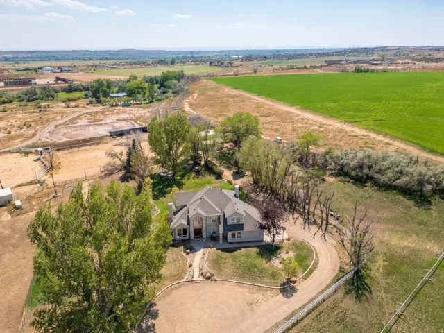 Expansive property featuring a circular driveway, mature trees, and a surrounding green landscape