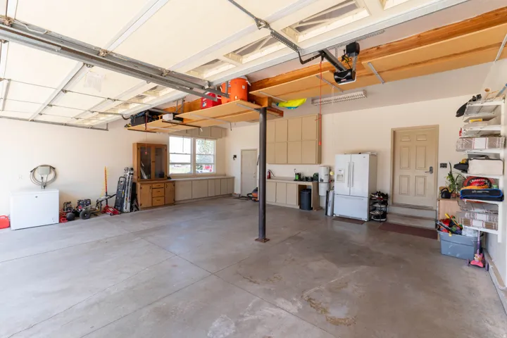 Expansive garage with concrete flooring, built-in cabinetry, dual windows, and an interior access door