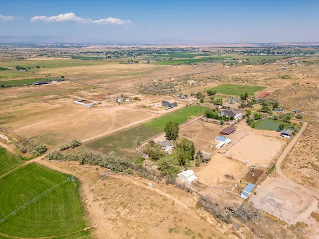 Expansive property with multiple structures, natural landscaping, a pond, and open fields