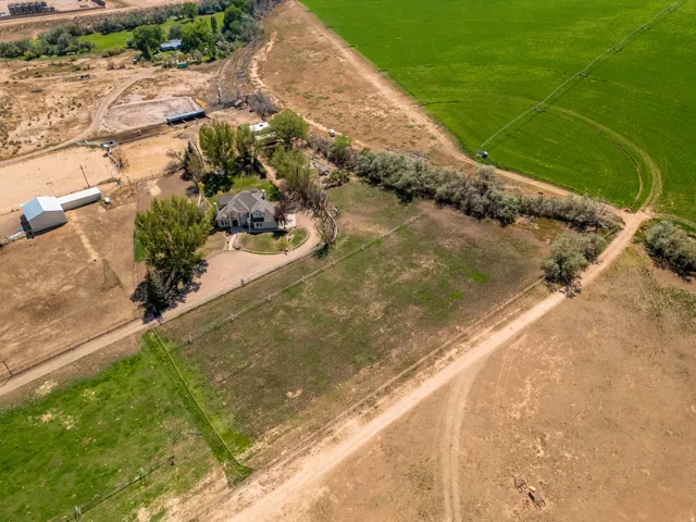 Expansive property featuring a central residence, a large outbuilding, an open field area, and established trees