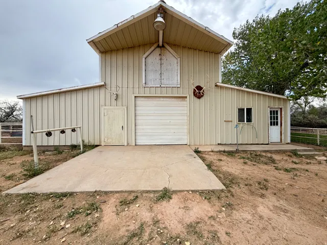 Two-story metal-sided structure with a central garage door, a side entry door, and a single window