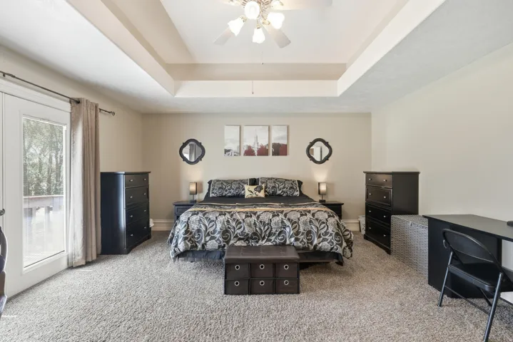 Tray ceiling, ceiling fan, neutral wall color, glass-paneled door, and neutral carpeting