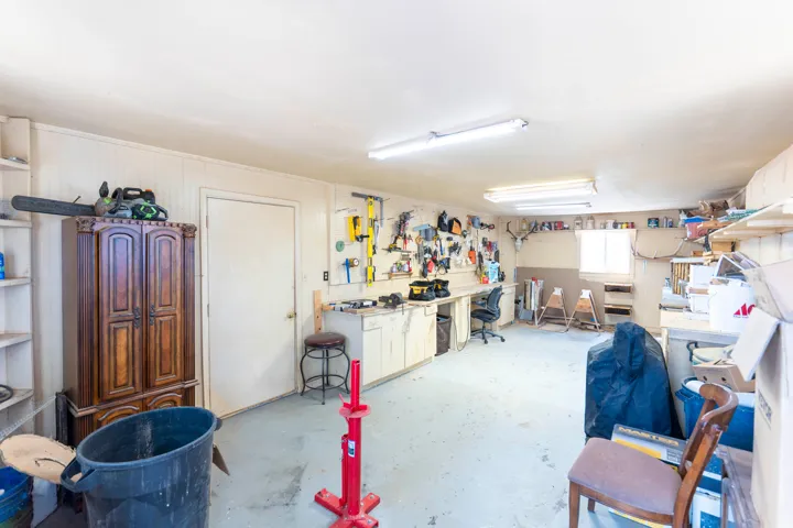 Spacious workspace featuring beadboard wall paneling, built-in shelving, and a concrete floor