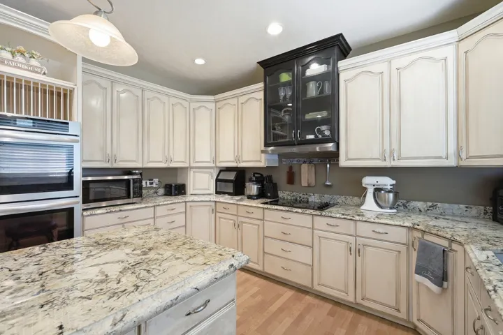 Wood-finish flooring with a kitchen island featuring a light-toned countertop