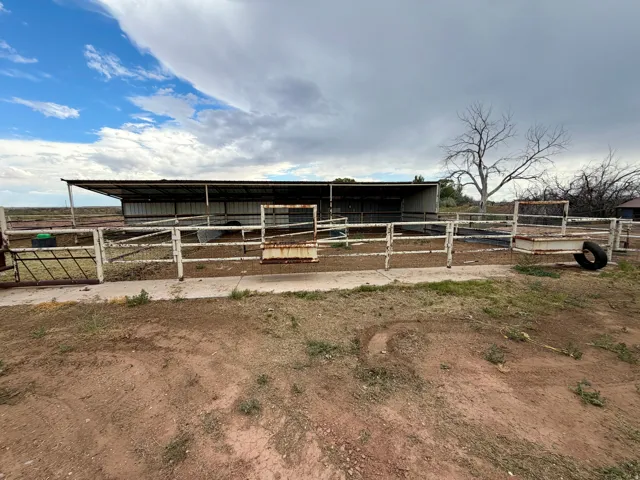 Metal-framed enclosure featuring a covered structure with an open-sided design, metal roofing, and corrugated metal siding