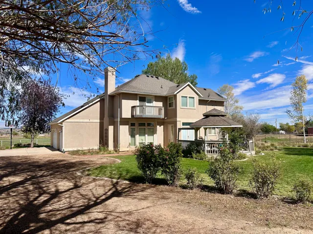 Stucco exterior, two-car garage, upper-level balcony, expansive lawn, and covered gazebo