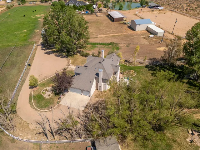 Expansive property featuring a multi-car driveway, detached outbuildings, a pond, and surrounding open fields