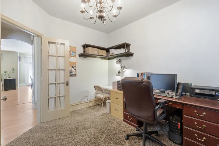 Wall-mounted shelving, French doors with glass panes, wood-finish flooring, and a decorative chandelier