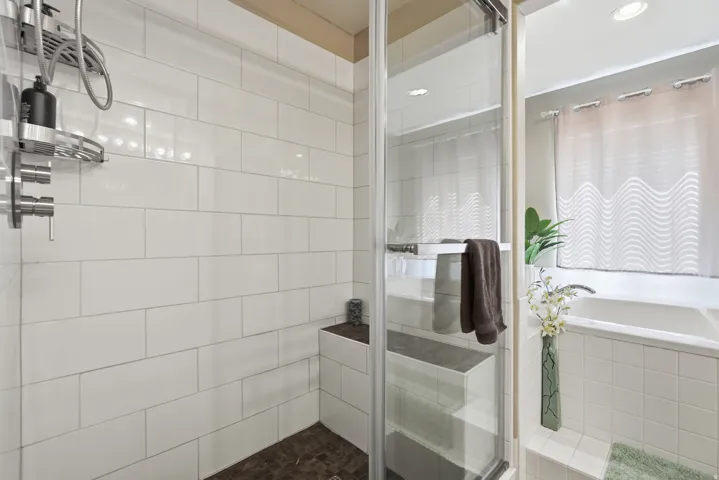 Shower with white subway tile, a built-in bench, and a glass enclosure