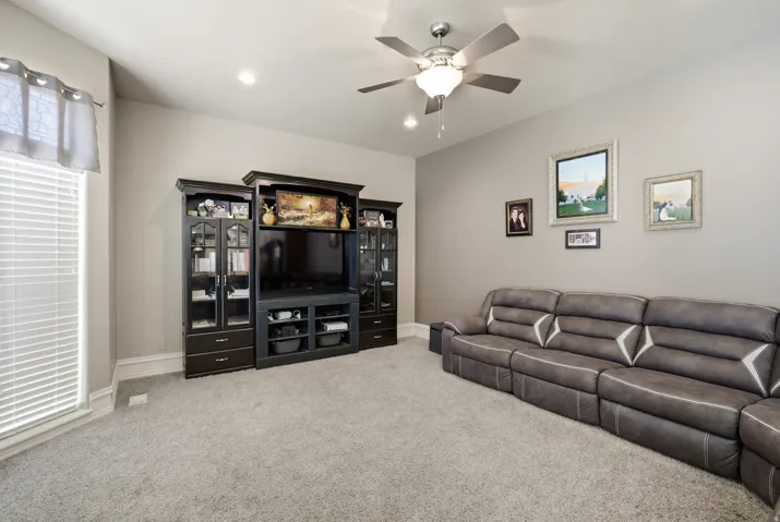 Built-in entertainment center, ceiling fan with integrated lighting, recessed lighting, wall-to-wall carpeting, and window with blinds