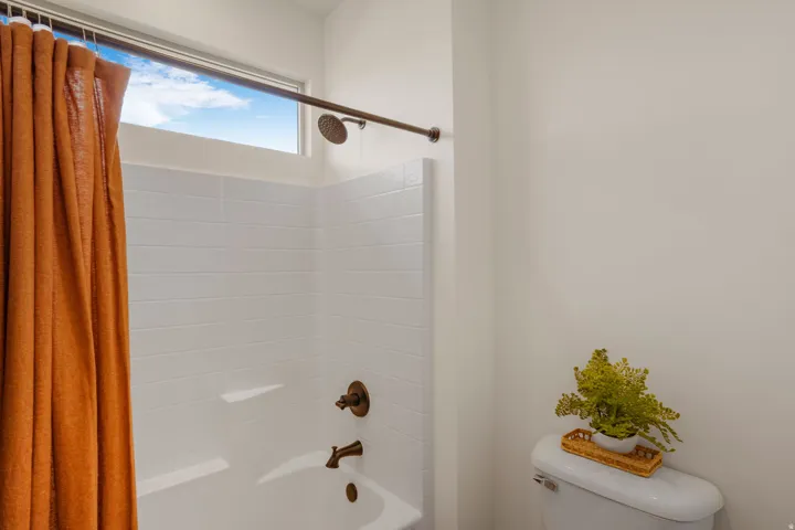 Bathtub and shower combination featuring white subway tile, a high transom window, and oil-rubbed bronze fixtures