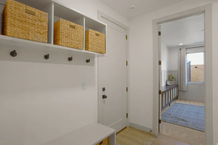 Built-in mudroom bench with cubby storage, wall hooks, and upper shelving