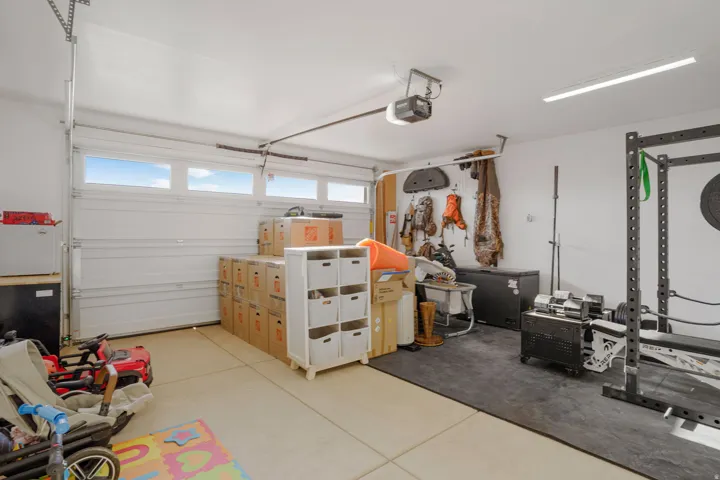 Attached garage with a sectional overhead door featuring integrated windows, concrete flooring, and a ceiling-mounted garage door opener