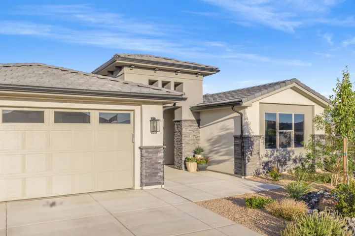 Contemporary stucco exterior featuring stone accents, a multi-pane garage door, and a tile roof