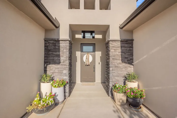 Modern entryway featuring a recessed front door, stacked stone columns, and stucco exterior finish