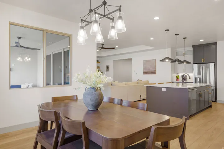 Open-concept living space featuring a dining area with a contemporary chandelier, a kitchen island with pendant lighting, wood-finish flooring, and recessed ceiling lights