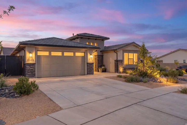 Contemporary stucco exterior with stone accents, featuring a two-car garage with transom windows