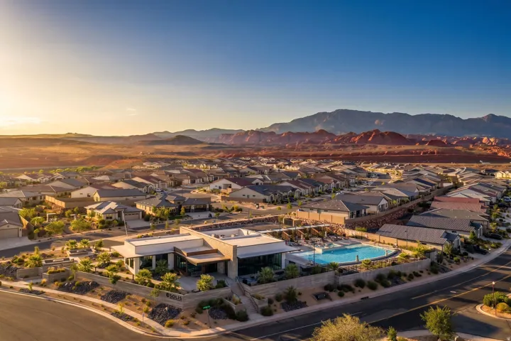 Community amenity building featuring a curved swimming pool, surrounding lounge areas, and desert landscaping