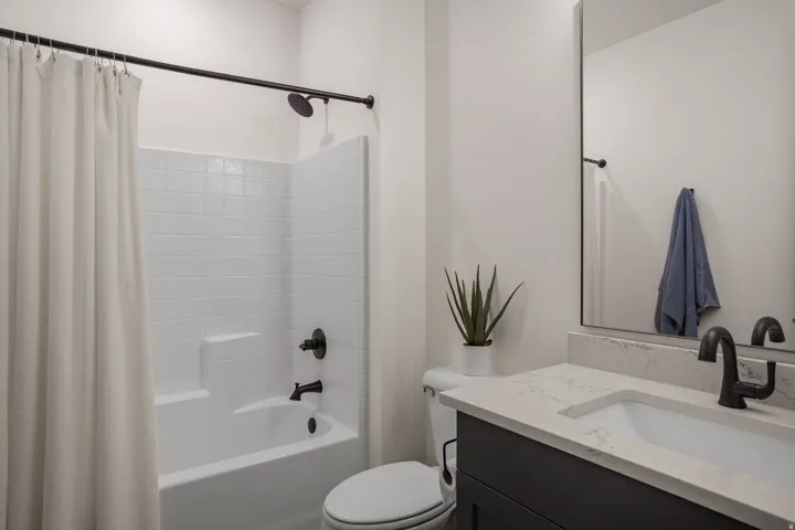 Bathroom featuring a tub/shower combination with subway tile surround, a single vanity with stone countertop, and matte black fixtures