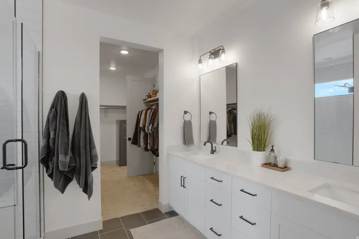 Dual vanity with white cabinetry, matte black hardware, and an integrated double sink