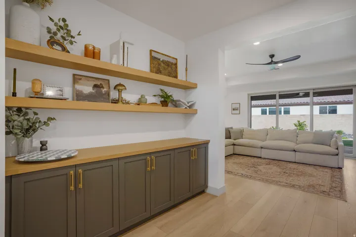 Built-in cabinetry with brass hardware, a light wood-finish countertop, and two floating shelves