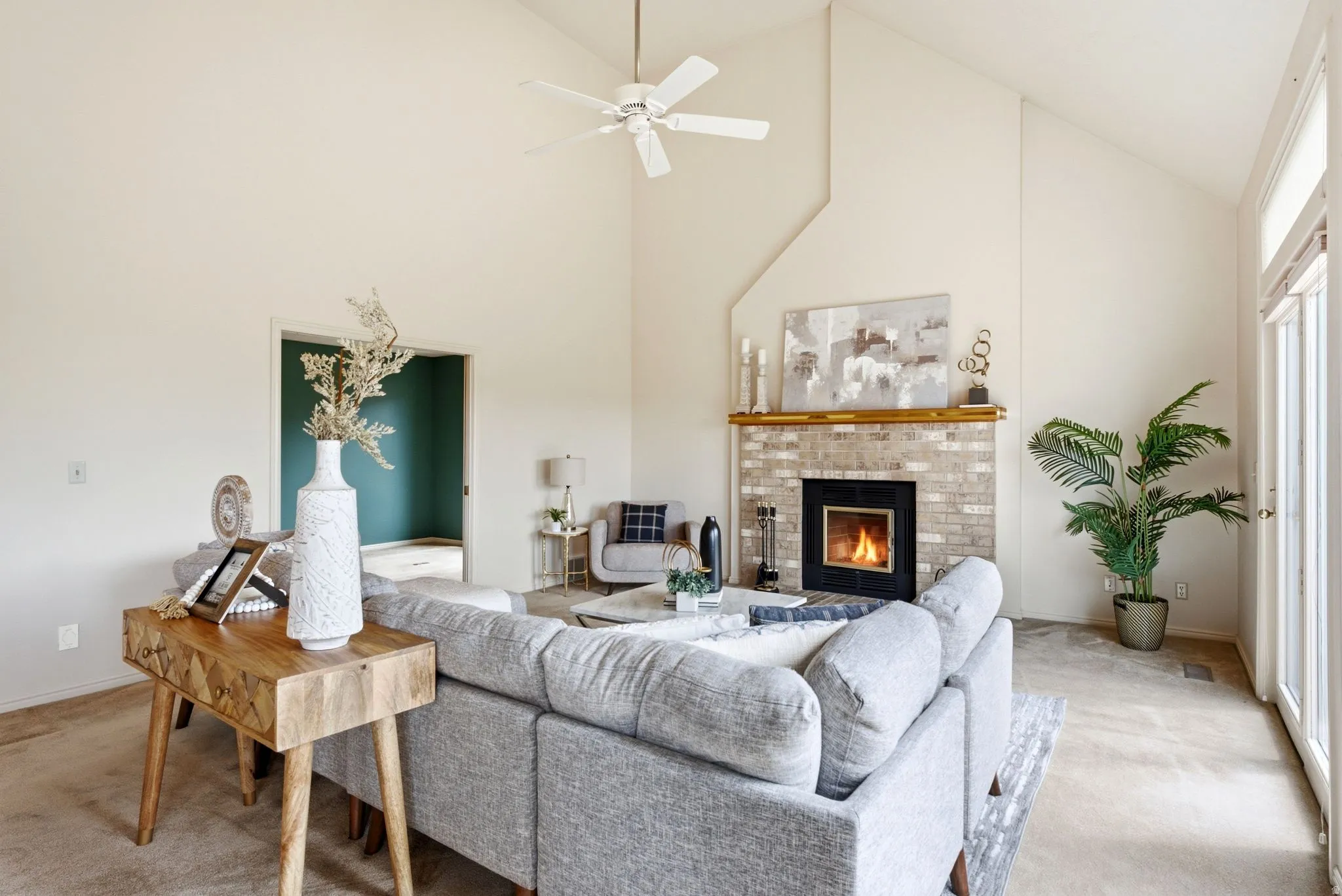 Spacious living area featuring vaulted ceilings, a brick fireplace with a wood mantel, and light-toned wall finishes