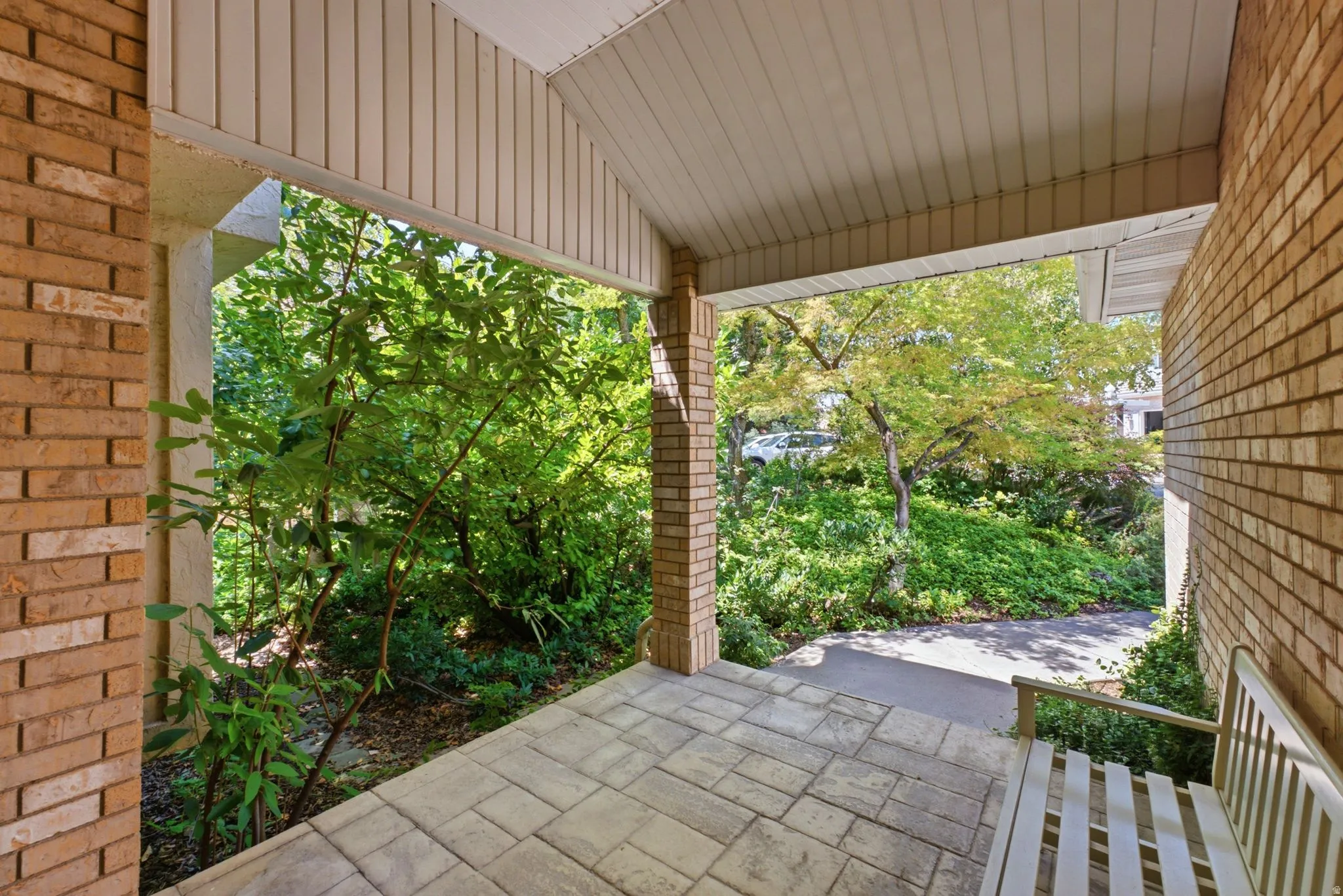 Covered entry porch featuring brick walls, an architectural post, and a paneled ceiling
