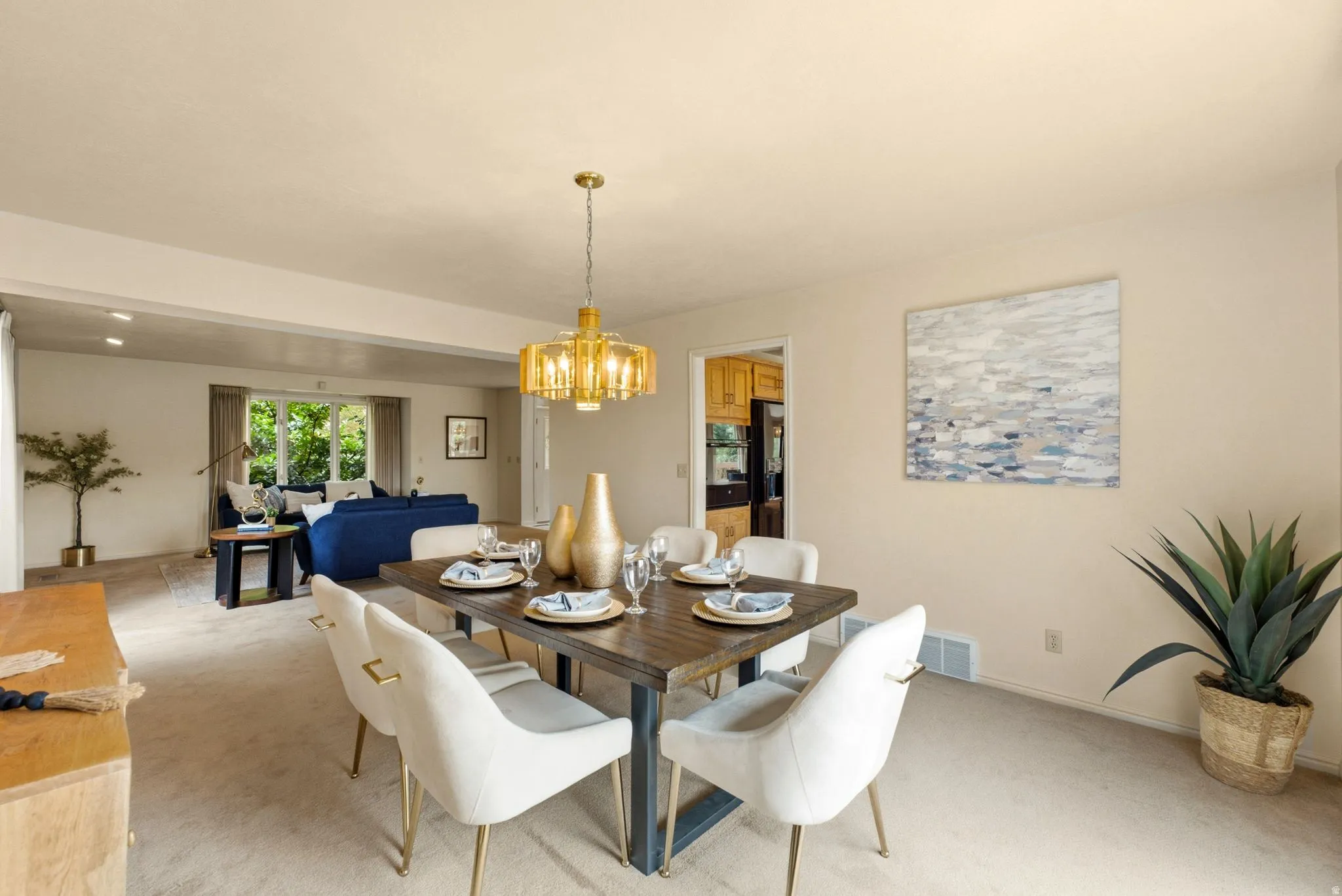Dining area featuring a modern brass chandelier, wood-finish tabletop, and carpet flooring