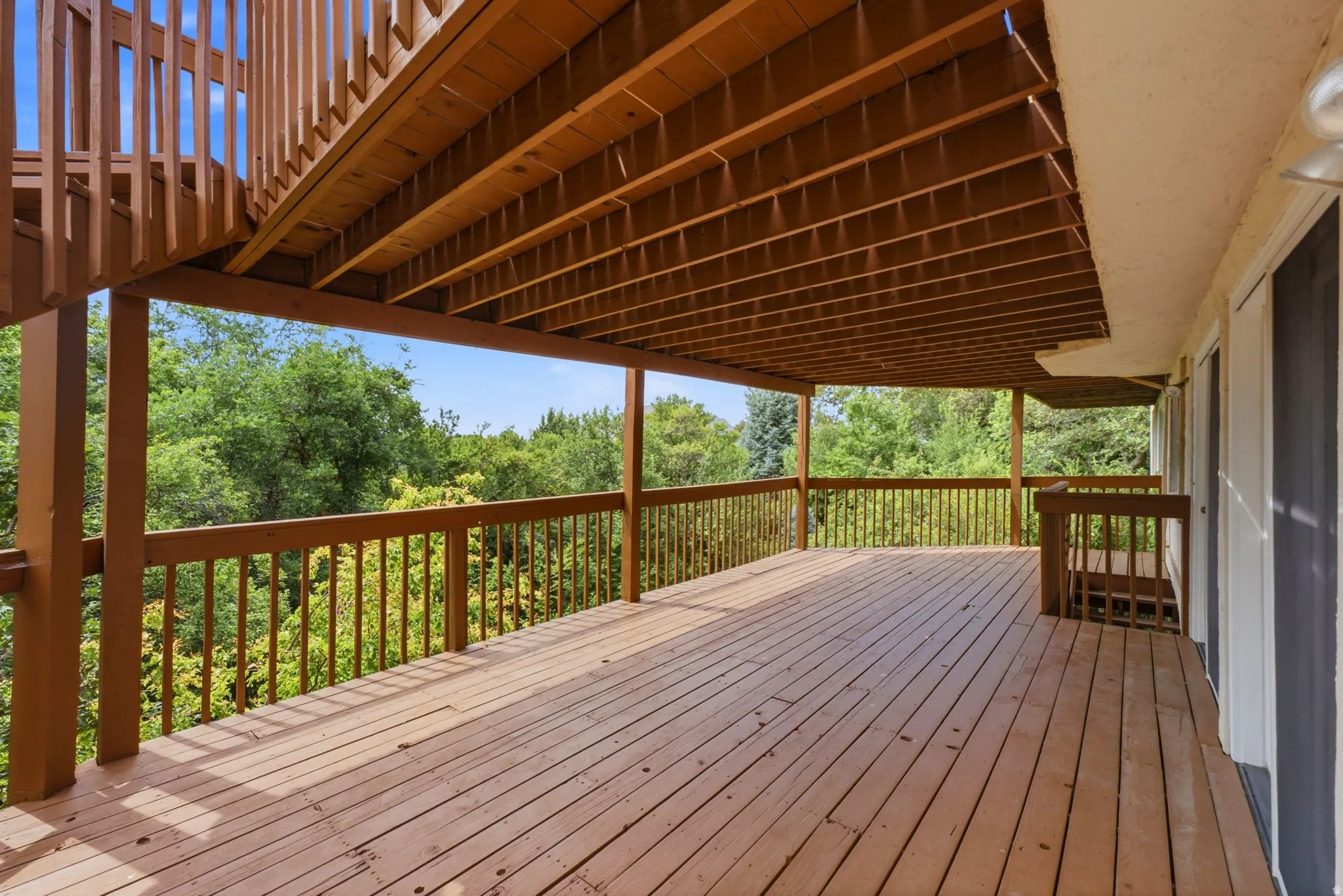 Expansive wood-finish deck with railings, providing an outdoor living space