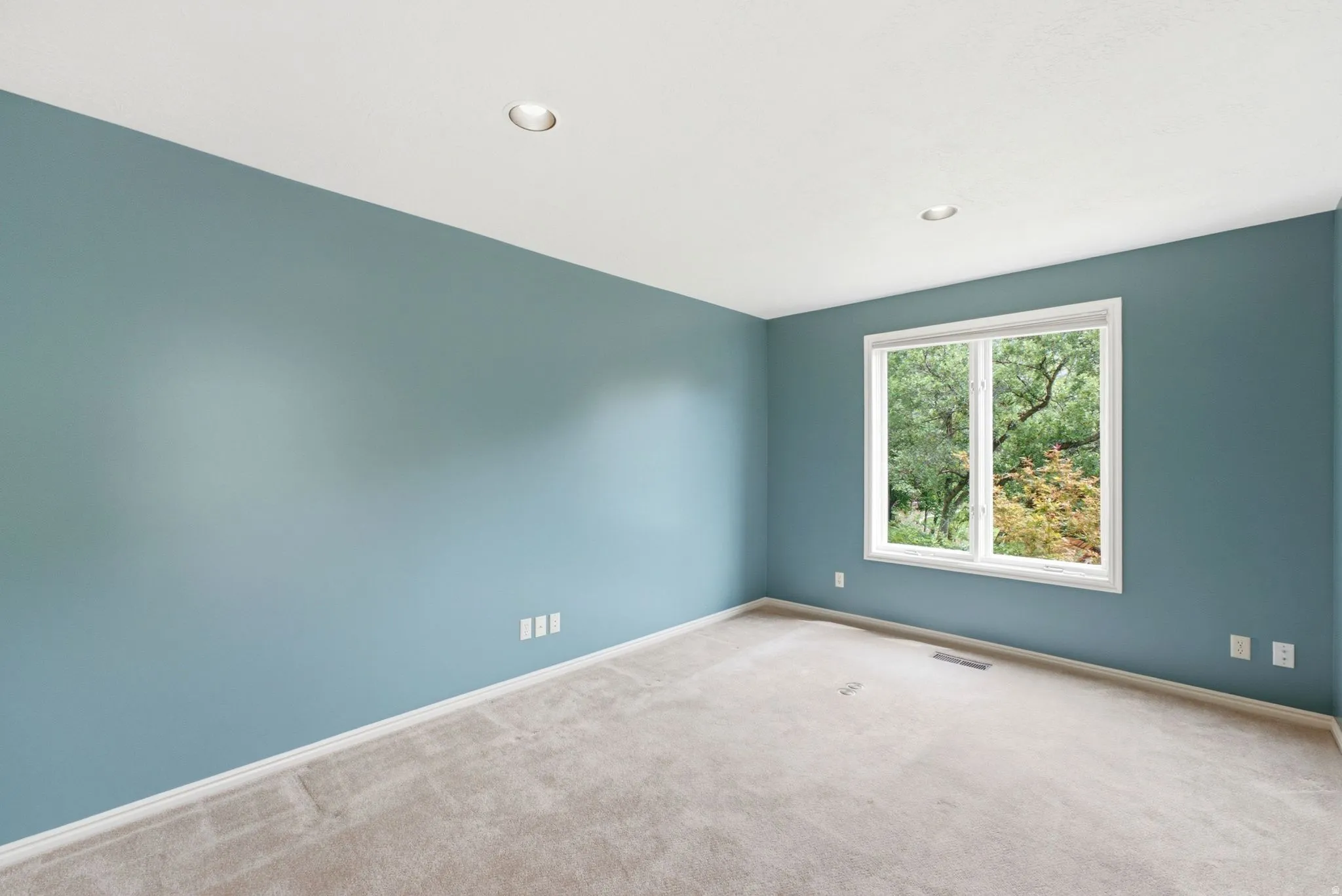 Room featuring a large window, recessed lighting, neutral carpet, and light blue walls