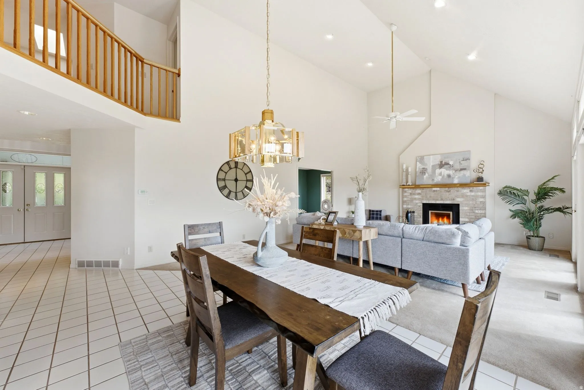Vaulted ceilings enhance the open-concept living space, featuring a fireplace with a light brick surround and wood mantel