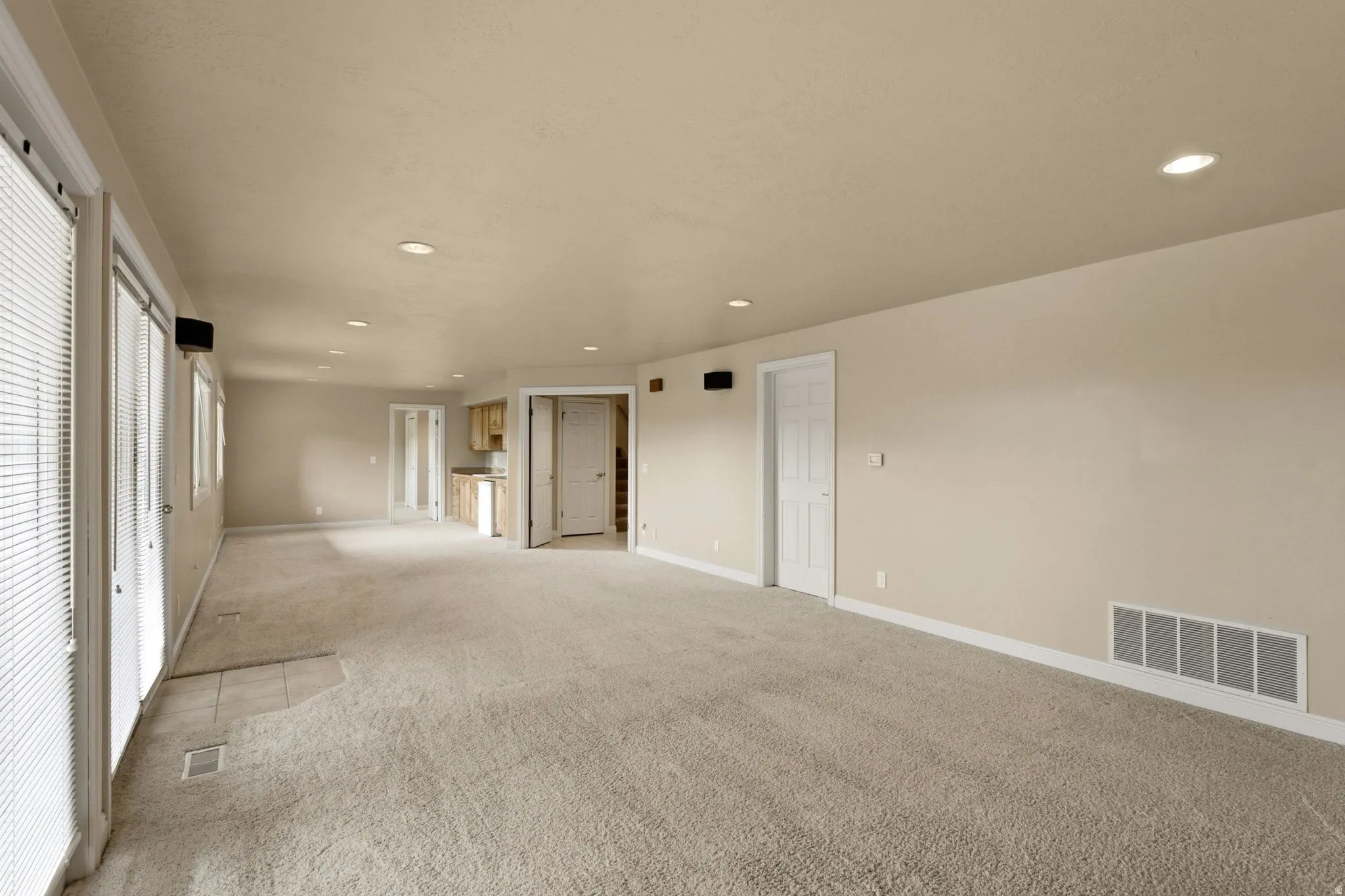 Expansive room with neutral carpet, recessed lighting, and multiple windows