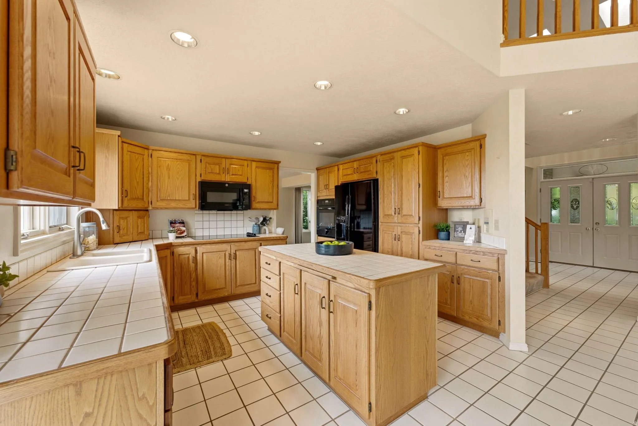Kitchen featuring wood cabinetry, tile countertops, tile flooring, recessed lighting, and a center island