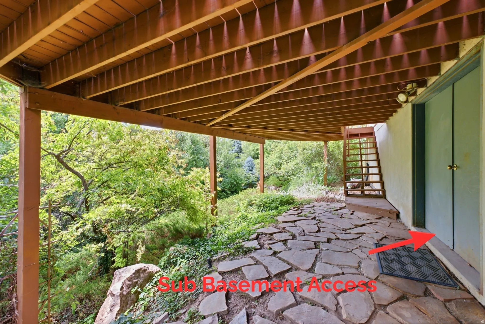 Covered outdoor patio with a flagstone path, accented by mature trees and natural rock formations