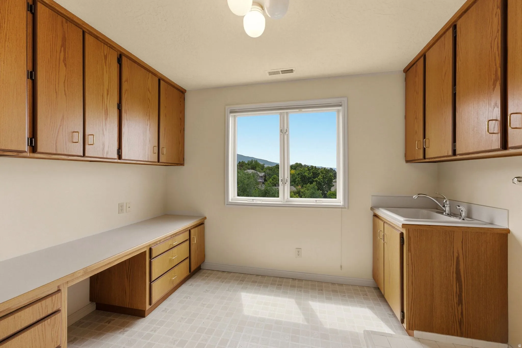 Extensive cabinetry and built-in desk space, utility sink, and a large window