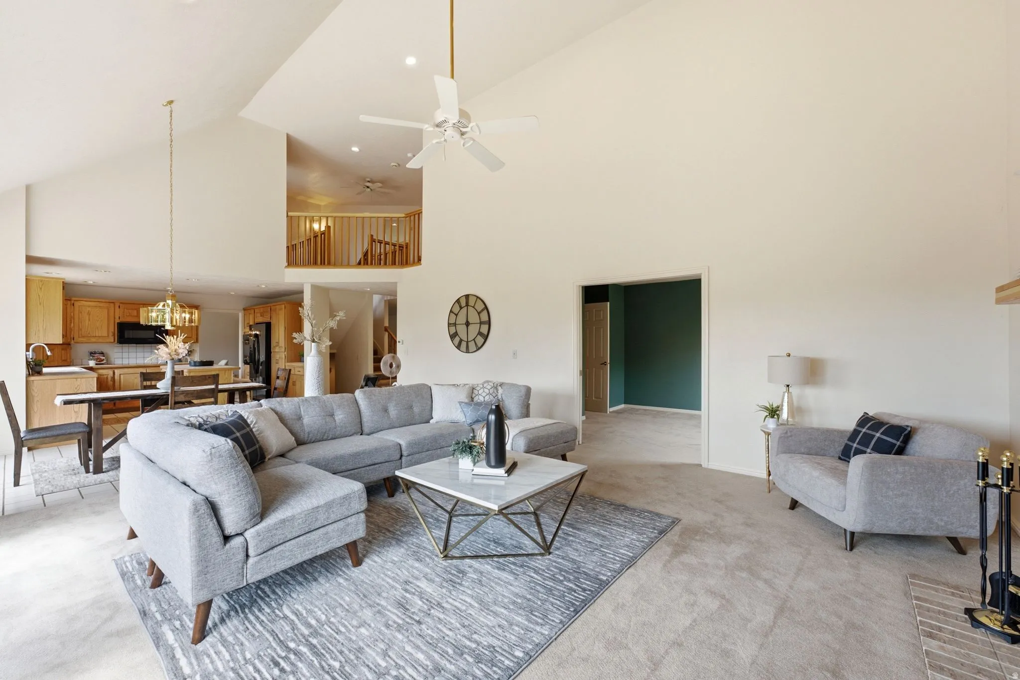Expansive living space featuring vaulted ceilings, a ceiling fan, and carpet flooring