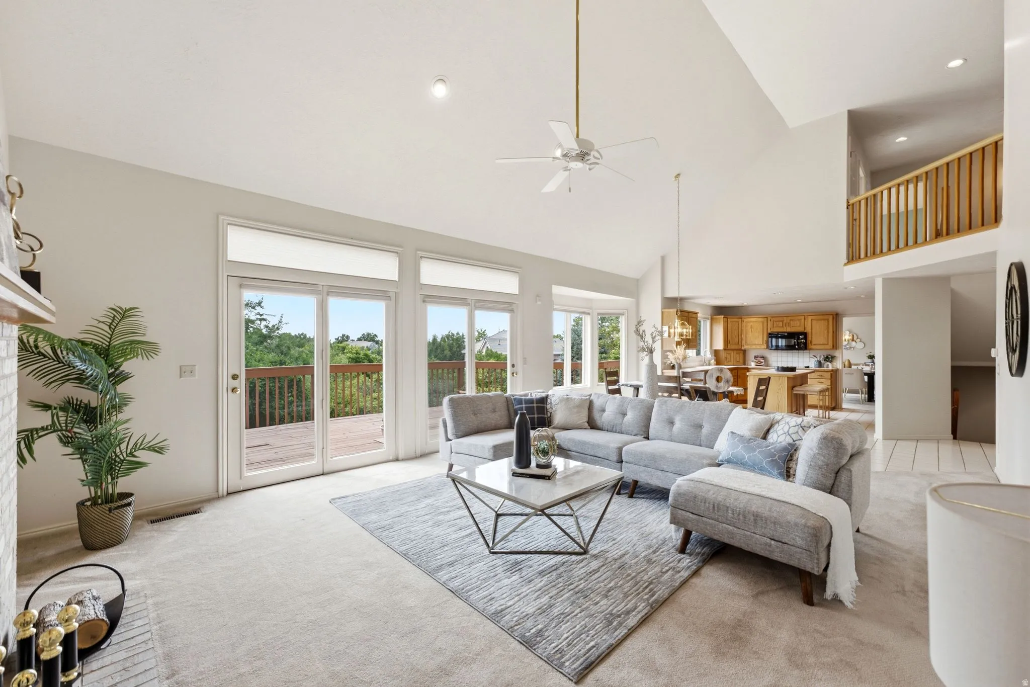 Vaulted ceilings define this living area, featuring multiple sliding glass doors opening to an outdoor deck