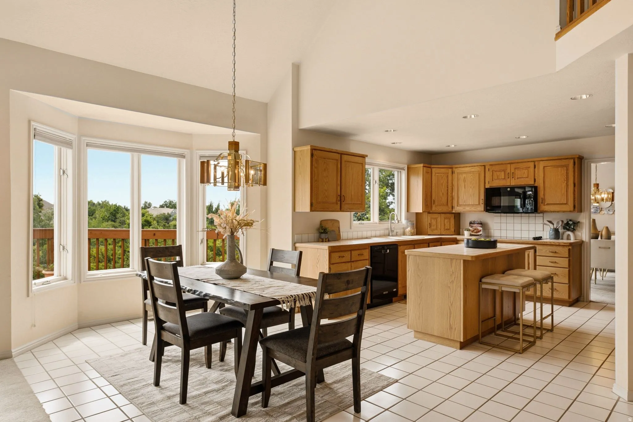 Bay window with natural light, light wood cabinetry, recessed lighting, central kitchen island, and square tile flooring