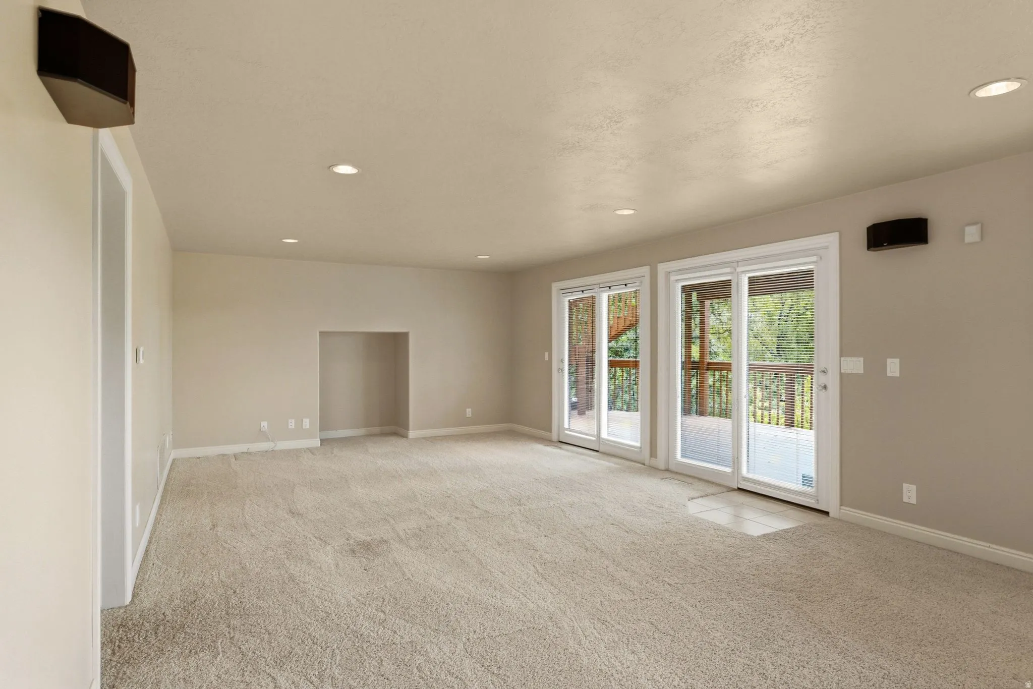 Recessed lighting illuminates the carpeted living space with a built-in alcove